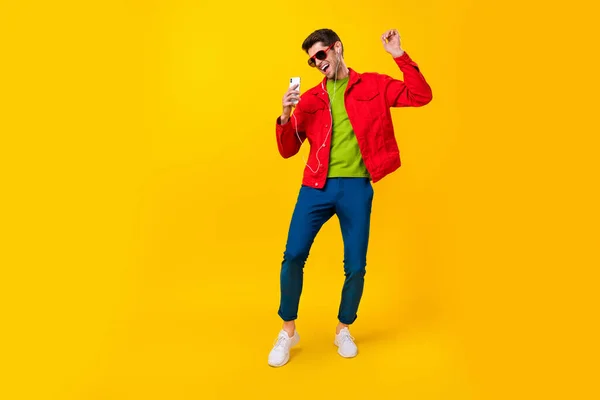 Pleine taille photo de impressionné millennial gars danse écouter musique porter lunettes veste jeans chaussures isolé sur fond jaune — Photo