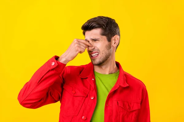Portrét atraktivní podrážděný chlap dotýkající se zavírání hluk špatný zápach izolované přes jasně žluté barvy pozadí — Stock fotografie