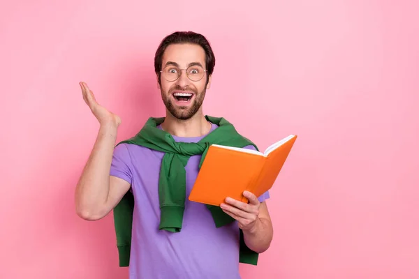 Foto de feliz impresionado hombre feliz averiguar información inesperada interesado en libro aislado sobre fondo de color rosa — Foto de Stock