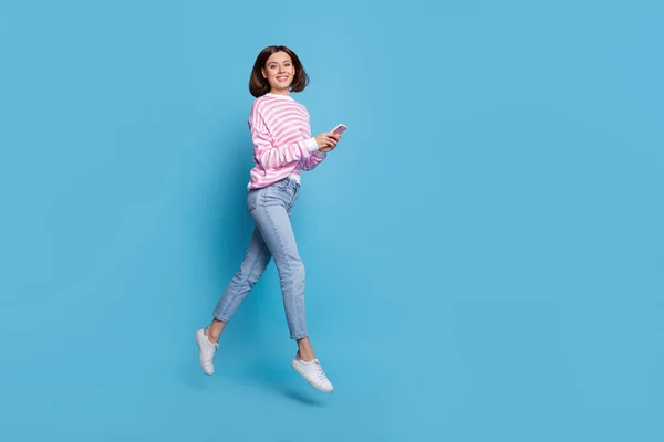 멋진 밀레니엄 아가씨의 전신 사진은 파란 배경에 고립된 전화기 셔츠진 신발을 신고 달려 있습니다. — 스톡 사진