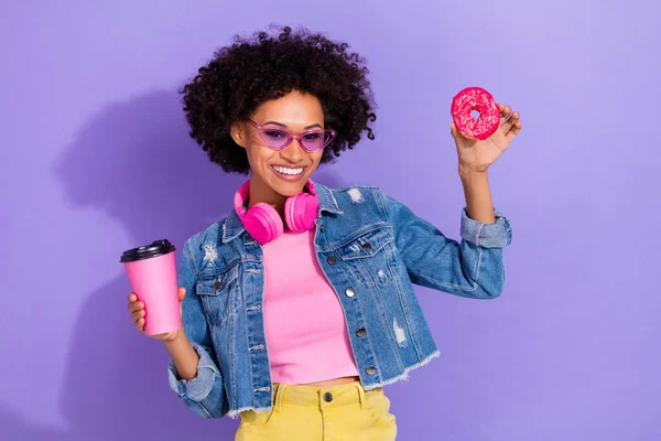 Photo of dreamy funny young woman wear jeans jacket headphones drinking tea eating biscuits isolated violet color background — ストック写真