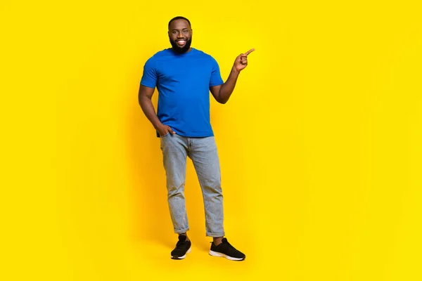 Full length body size view of attractive cheerful guy showing copy space ad isolated over bright yellow color background — ストック写真