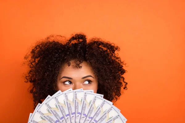 Portret van aantrekkelijke trendy grappig mysterieus meisje met geld verbergen gezicht geïsoleerd over fel oranje kleur achtergrond — Stockfoto