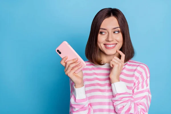 Fénykép a bájos Y-generációs barna hölgy tartsa telefon néz promo kopás csíkos pulóver elszigetelt kék háttér — Stock Fotó