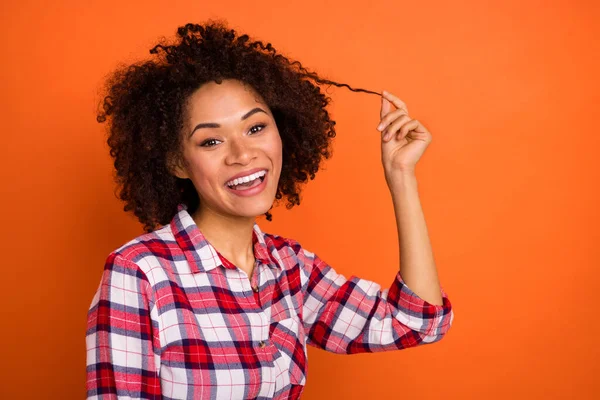 Photo of nice millennial brunette lady touch hair wear plaid shirt isolated on orange color background — Stock Photo, Image