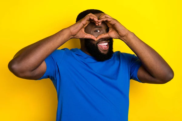 Porträtt av attraktiv glad kille som visar tittar genom hjärtat tecken amour match isolerad över levande gul färg bakgrund — Stockfoto