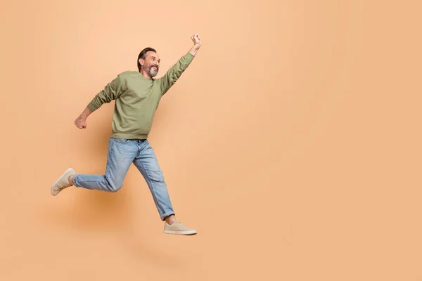 Foto de perfil de comprimento total do homem animado enérgico levantar mão olhar espaço vazio isolado no fundo cor bege — Fotografia de Stock