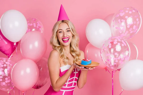 Foto de senhora engraçado segurar prato de peça de bolo tem aniversário divertido desgaste cone chapéu fantasia vestido listrado isolado cor rosa fundo — Fotografia de Stock