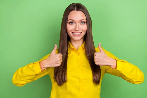 Photo de belle jeune femme brune coiffure pouce vers le haut porter chemise jaune isolé sur fond de couleur verte — Photo