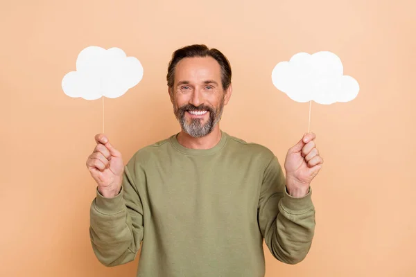 Ritratto di attraente uomo allegro tenendo in mano le nuvole annuncio copiare spazio isolato su sfondo di colore beige pastello — Foto Stock