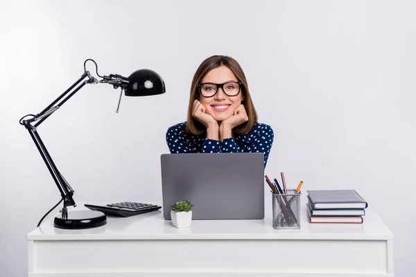 Photo of cheerful positive person hands on chin sit behind workstation isolated on grey color background — Stock Photo, Image