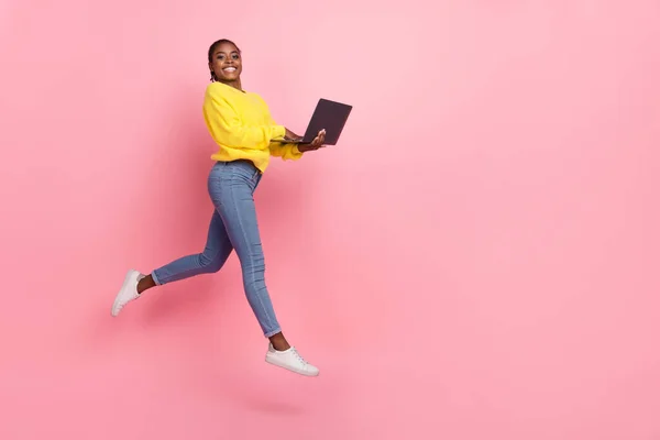 Pleine longueur profil côté photo de jeune fille joyeuse utilisation ordinateur portable saut représentant isolé sur fond de couleur rose — Photo