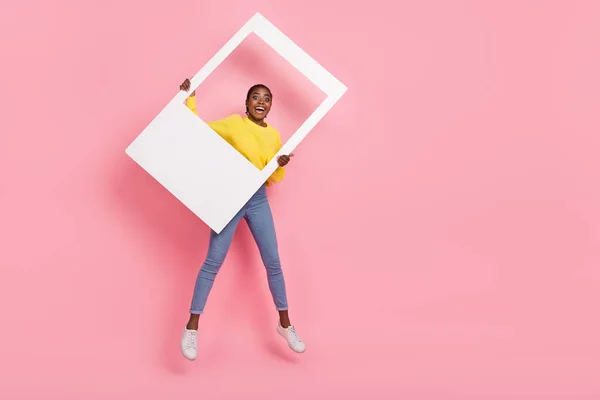 Foto de corpo inteiro de jovem alegre enérgico menina salto segurar quadro janela álbum isolado sobre cor rosa fundo — Fotografia de Stock