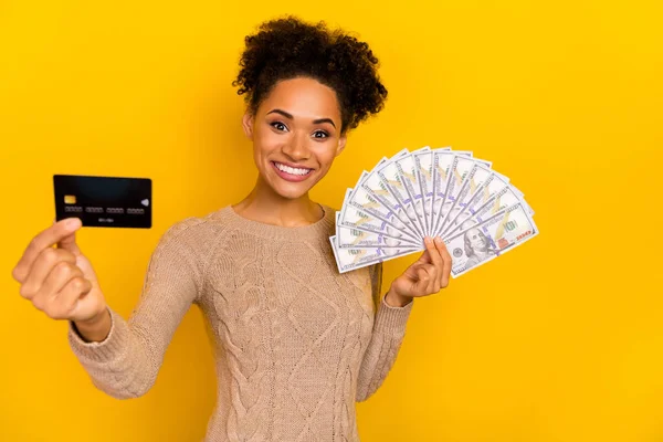 Foto van mooie duizendjarige brunette dame houden kaart geld dragen pullover geïsoleerd op gele kleur achtergrond — Stockfoto