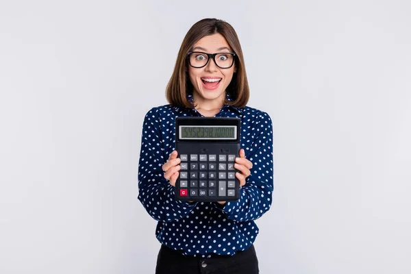 Portret atrakcyjnej wesołej dziewczyny pokazujący ilość kalkulatora odizolowanego od szarego pastelowego tła — Zdjęcie stockowe