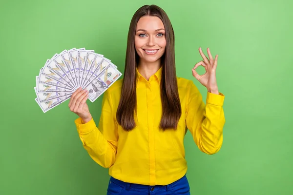 Neşeli genç kızın fotoğrafı parmaklarını göster tamam sembol para kazancı yeşil arkaplan üzerinde büyük izole önerilir — Stok fotoğraf