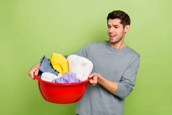 Photo of millennial sad brunet guy do laundry wear shirt isolated on green color background — Fotografia de Stock