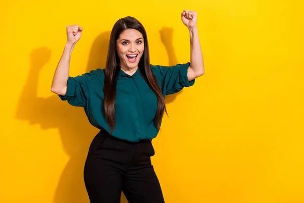 Photo of pretty lucky lady dressed green shirt smiling rising fists empty space isolated yellow color background — Stockfoto