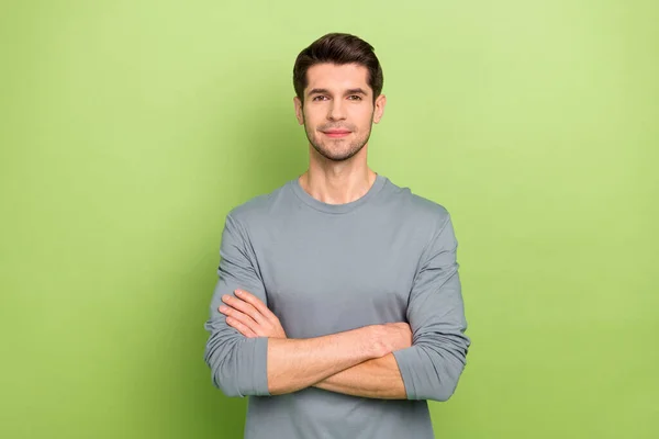 Photo of good millennial brunet guy crossed arms wear grey shirt isolated on green color background — Stock Photo, Image