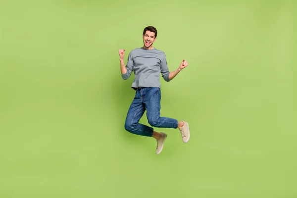 Full size photo of overjoyed crazy delighted man jumping in excitement win money lottery isolated on green color background — ストック写真