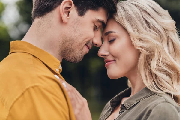 Cropped profile side view portrait of attractive sweet cheerful sweet couple enjoying cuddling on fresh air outdoors — стоковое фото