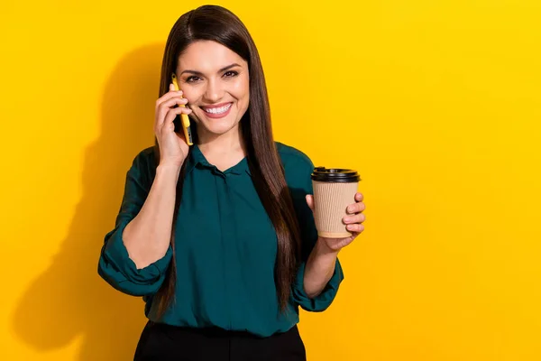 Photo of young cheerful woman communication say tell mobile drink latte caffeine isolated over yellow color background — 스톡 사진