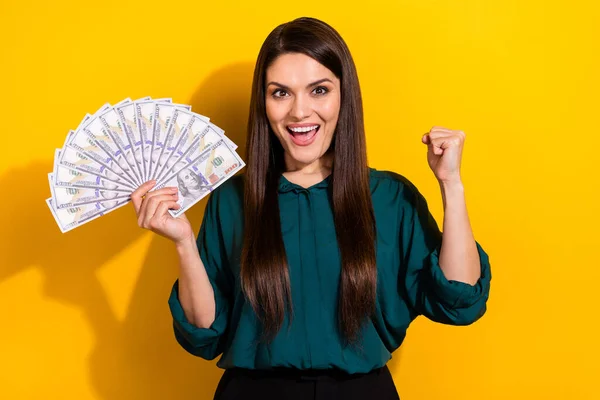Photo of pretty lucky woman wear green shirt rising fist holding dollars fan isolated yellow color background — 스톡 사진