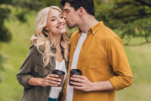 Retrato de amoroso bonito bonito alegre casal passar fim de semana bebendo latte beijos flertando ao ar livre — Fotografia de Stock