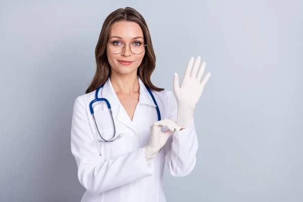 Foto de la joven mujer bonita poner guantes de goma ginecólogo chequeo laboratorio aislado sobre fondo de color gris — Foto de Stock