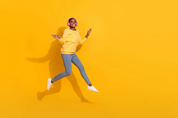 Full längd kroppsstorlek bild av attraktiva trendiga glada flicka hoppa lyssna popkopia utrymme isolerad över ljusa gula färg bakgrund — Stockfoto