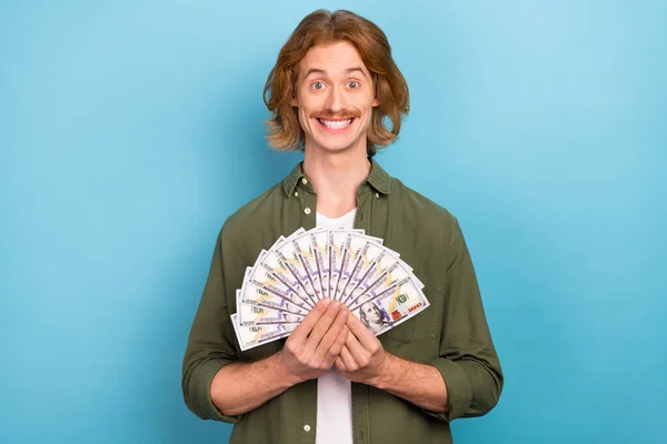 Portrait of attractive funky cheerful guy holding us dollars 100 atm cash back isolated over pastel blue color background — Stockfoto