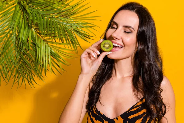 Photo of young pretty woman eat fresh yummy kiwi exotic fruit dream isolated over yellow color background — Fotografia de Stock