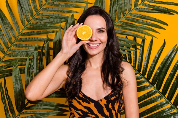 Photo of young cheerful woman cover eye orange organic bio therapy isolated over yellow color background — 스톡 사진