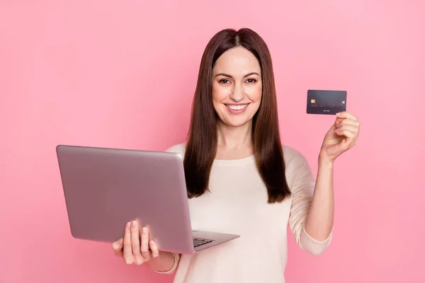 Foto av fantastisk vacker kvinna hålla ny modell laptop köpa online använda kreditkort bära fin pullover isolerad rosa färg bakgrund — Stockfoto