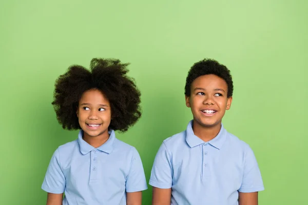 Portrait of two attractive cheerful trendy pre-teen schoolkids creating solution isolated over green color background — Stock Photo, Image