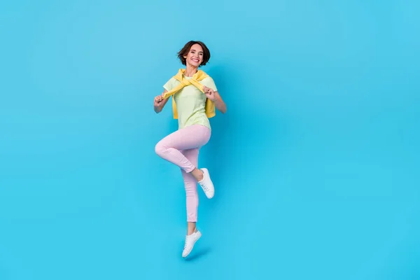 Full size photo of pretty young brunette lady jump wear t-shirt pants shoes isolated on blue background — Stock Fotó