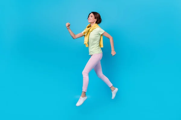 Foto de perfil de corpo inteiro de impressionado millennial morena senhora executar desgaste t-shirt calças sapatilhas isoladas no fundo azul — Fotografia de Stock