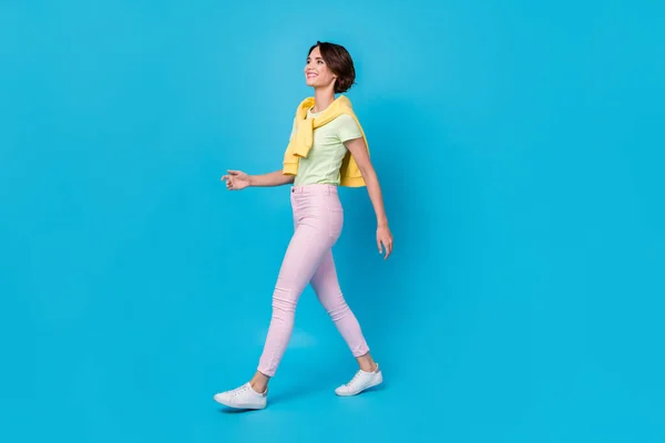 Full storlek foto av vackra unga brunett dam gå bära t-shirt byxor skor isolerad på blå bakgrund — Stockfoto