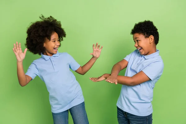 2つの魅力的なトレンディーな明るい前ティーンの子供たちの肖像緑の色の背景に隔離された楽しみを持って動いて踊る — ストック写真