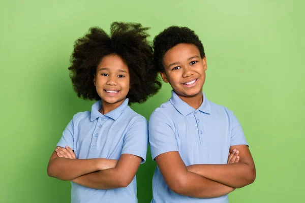Портрет двох привабливих веселих модних дітей зі складеними руками академічний урок мислення ізольовано на фоні зеленого кольору — стокове фото