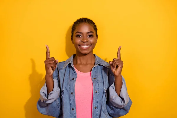 Foto av ung glad flicka visar fingrarna tomt utrymme rekommenderar att välja banner isolerad över gul färg bakgrund — Stockfoto