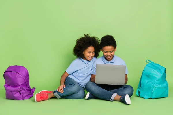 Portrait of attractive cheery pre-teen trendy friends friendship sitting using computer web website media isolated on green color background — 스톡 사진