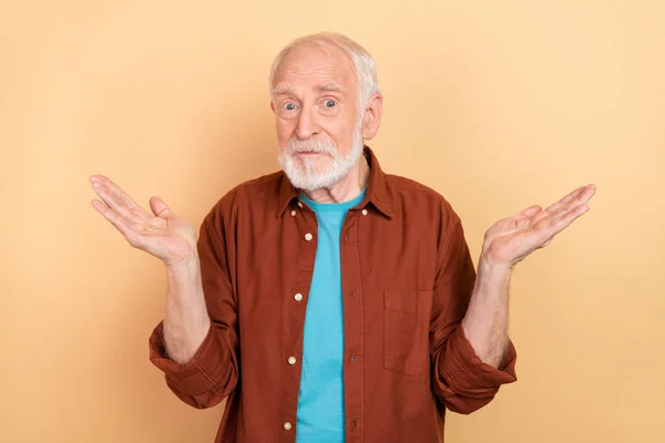 Foto de inseguro velho penteado branco homem ombros encolher de ombros usar camisa marrom isolado no fundo cor bege — Fotografia de Stock