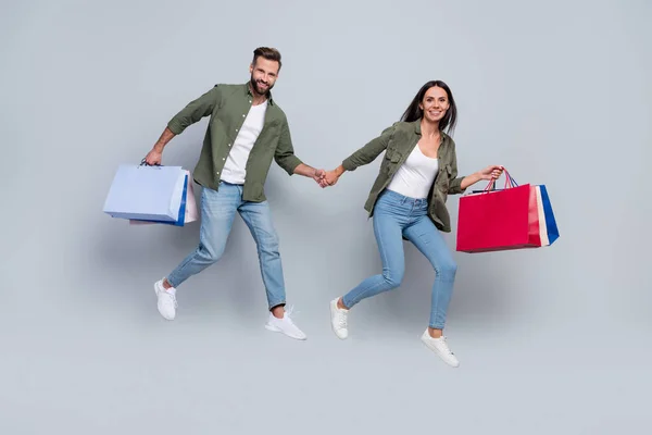 Full length photo of lady guy jump run fast boutique buy shopping bags isolated over grey color background — Stok fotoğraf