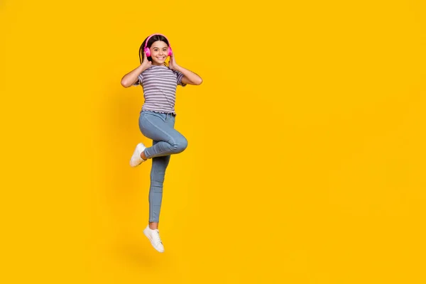 Full length photo of young cheerful lady listen radio earphones jump mp3 melody isolated over yellow color background — Stok fotoğraf