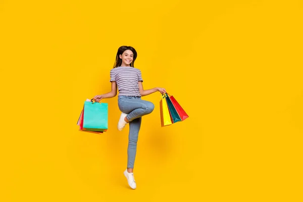 Teljes hosszúságú fotó fiatal lány ugrás bevásárló bolt nyaralás jelen elszigetelt sárga szín háttér — Stock Fotó
