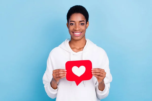 Photo of attractive beautiful unisex lady dressed white hoodie showing heart like card isolated blue color background —  Fotos de Stock
