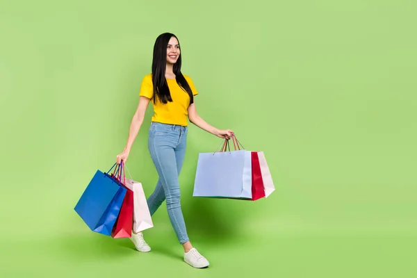 Full body profile portrait of pretty positive person hold packages look empty space isolated on green color background — Stockfoto
