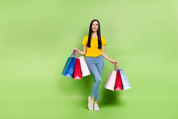 Full body photo of gorgeous positive person hold packages look empty space isolated on green color background — Stok fotoğraf