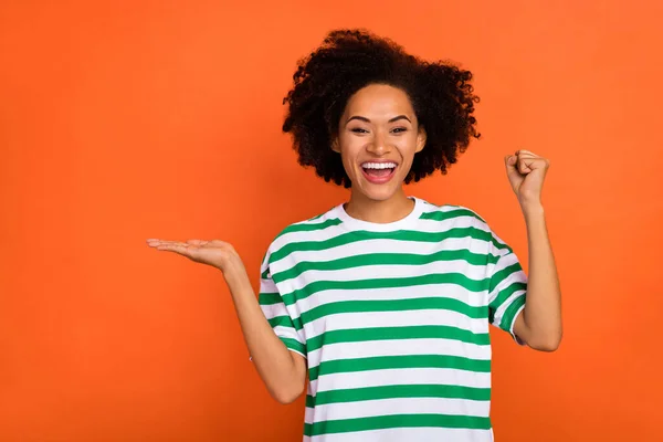 Porträtt av attraktiva glada vågiga hår flicka glädje med roligt innehav kopia utrymme annons isolerad över ljusa orange färg bakgrund — Stockfoto